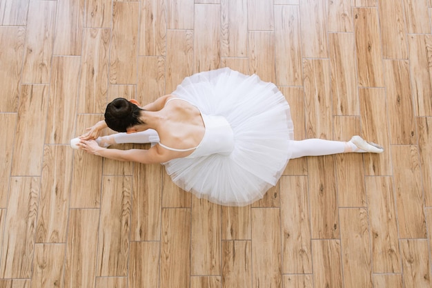 Foto ballerina caucasica con scarpe a punta sullo sfondo bianco del pavimento in legno