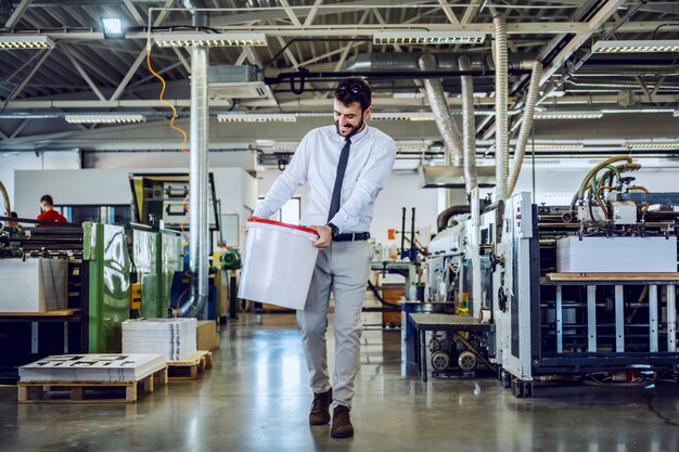 caucasian bearded graphic engineer carrying bucket with liquid glue