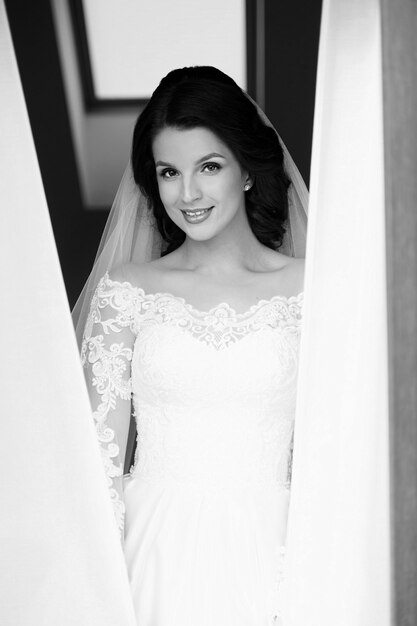 caucasian beautiful woman bride in traditional european white dress standing by the window