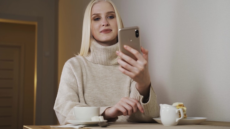Photo caucasian beautiful young female siting at cafe terrace and recording voice message on smartphone. stylish woman talking and sending audio record on mobile phone.