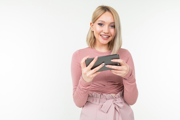 Caucasian blond girl in pink clothes plays on the phone