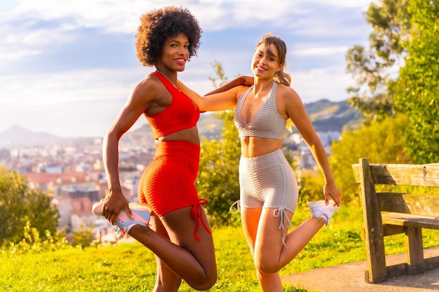 Caucasian blonde girl and dark-skinned girl with afro hair doing stretching