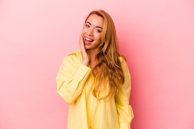 Caucasian blonde woman isolated on pink background shouts loud, keeps eyes opened and hands tense.