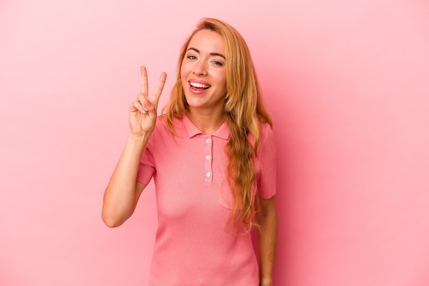 Caucasian blonde woman isolated on pink background showing number two with fingers.