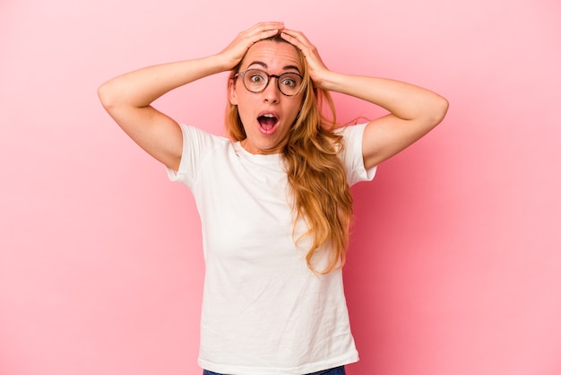 Caucasian blonde woman isolated on pink background surprised and shocked.