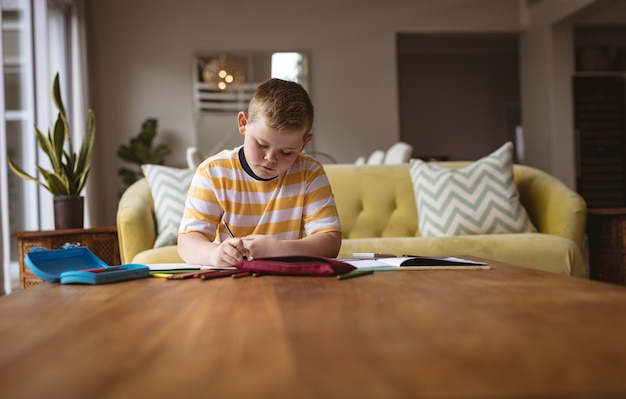 Photo caucasian boy drawing in his book sitting in the living room at home