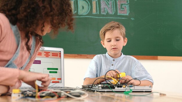 Photo caucasian boy fixing main board by using screwdriver at stem lesson pedagogy