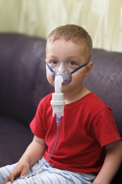 Photo caucasian boy inhales couples containing medication to stop coughing.