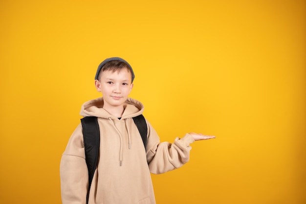 Foto il ragazzo caucasico sta pubblicizzando qualcosa che punta allo spazio libero dello studio giallo ragazzo che tiene qualcosa sul palmo della mano