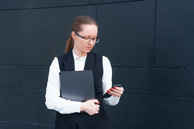 Caucasian business lady in suit holding laptop and talking on phone posing