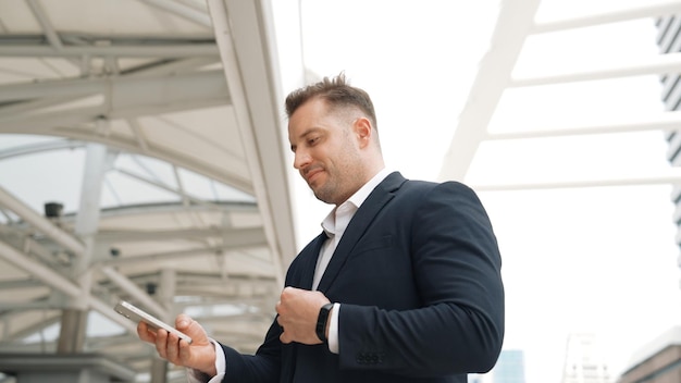 Caucasian business man checking mobile phone while standing at urban Urbane