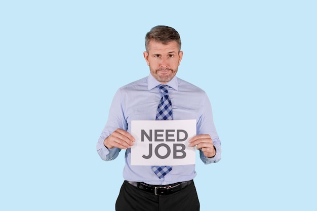 Caucasian business man holds up a cardboard sign with the words Need job