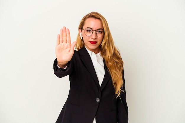 Caucasian business woman wearing a wireless headphones isolated on white background standing with outstretched hand showing stop sign, preventing you.