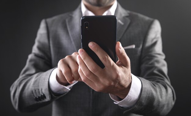 Uomo d'affari caucasico che utilizza smartphone in ufficio.