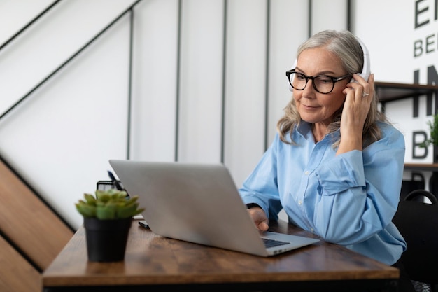 Caucasian businesswoman in headphones watching webinar on laptop in office