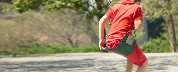 Caucasian child boy is swinging on a swing