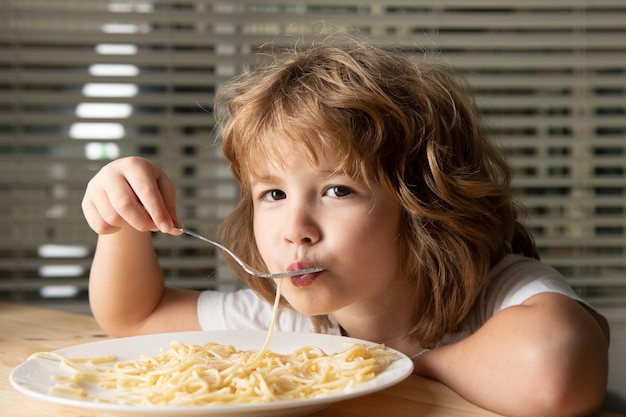 Caucasian child eating pasta, spaghetti. Kids funny face.