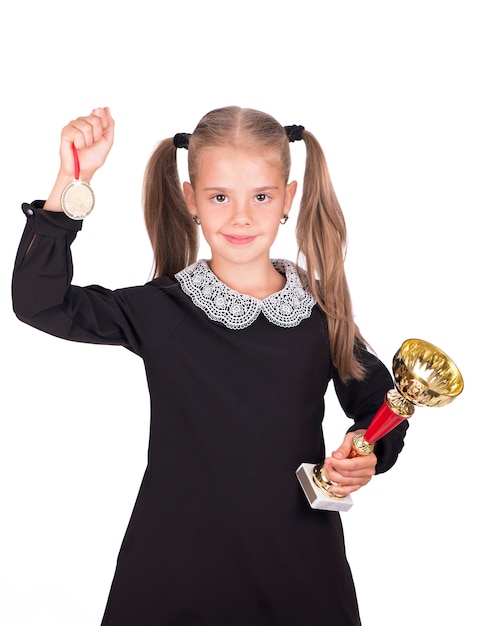 La ragazza caucasica del bambino tiene la tazza e la medaglia isolate su fondo bianco.