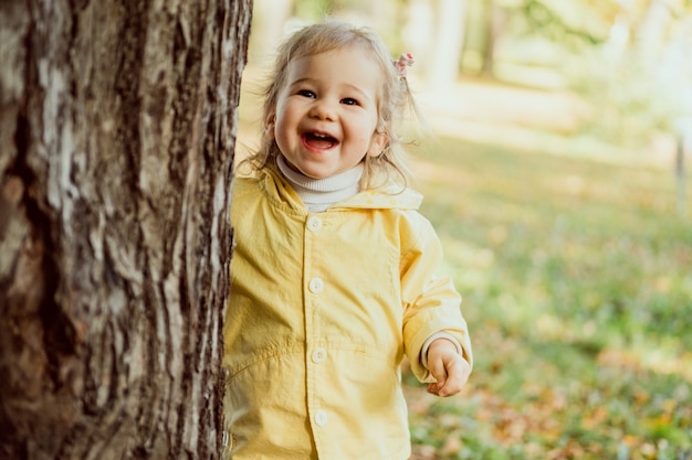 Caucasian child girl laughing walking in the park near a tree.