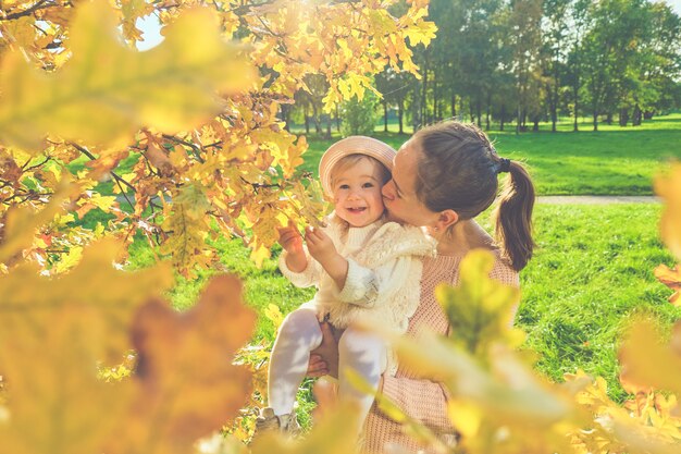 Caucasian child girl with mom near the autumn tree