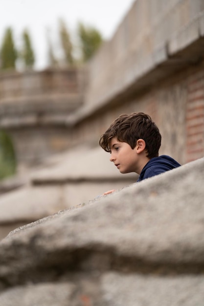 Caucasian child looks away from behind a wall