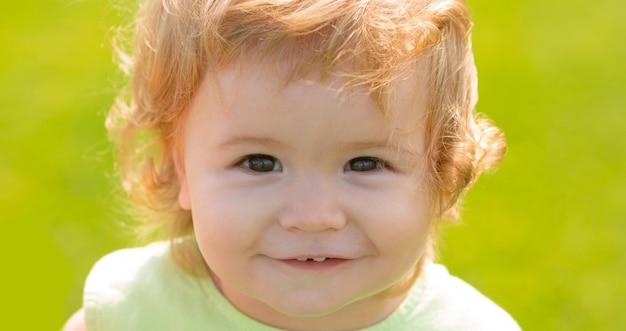 Кавказский детский портрет крупным планом. Детское лицо. Улыбающийся младенец, милая улыбка. Летний открытый парк.