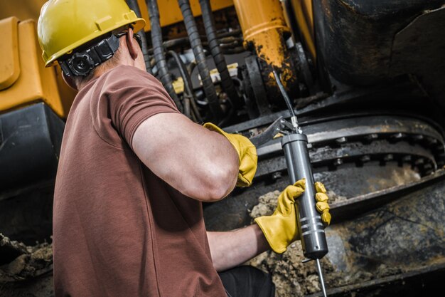 Photo caucasian construction worker performing excavator maintenance