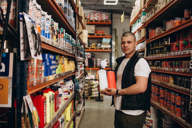 Caucasian consultant in uniform at hardware store Male standing next to shelves with tools at store