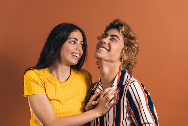Caucasian couple playing smiling together in front of a brown wall