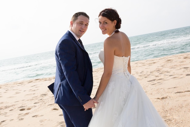 Caucasian couple wedding on the beach side walking on sand