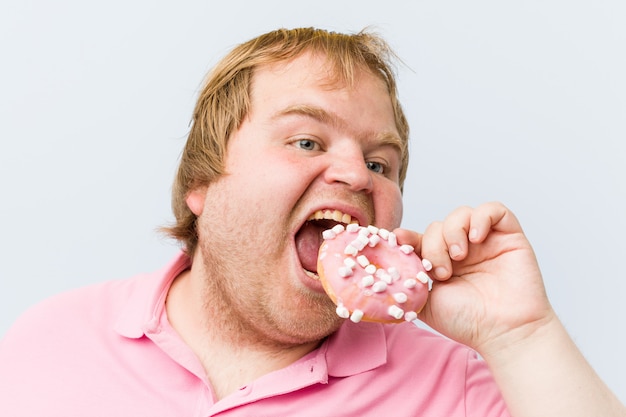 Caucasian crazy blond fat man holding a donuts