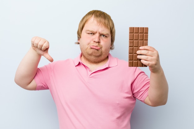 Кавказский сумасшедший белокурый мужчина держит шоколадный планшет