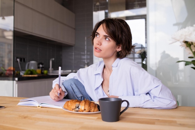 白人のかわいい女性は目をそらし、キッチンで考えています