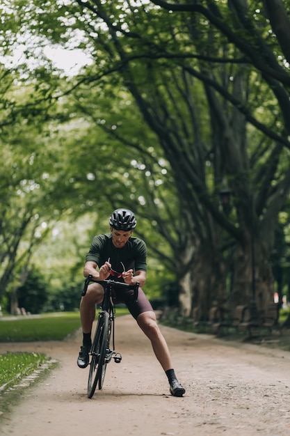Кавказский велосипедист в спортивной одежде и шлеме отдыхает в парке