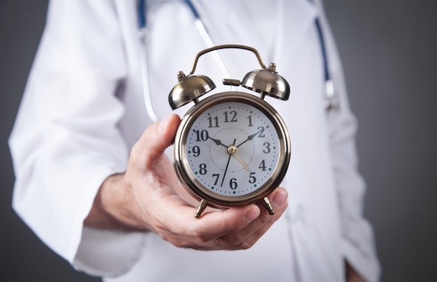 Caucasian doctor holding alarm clock.