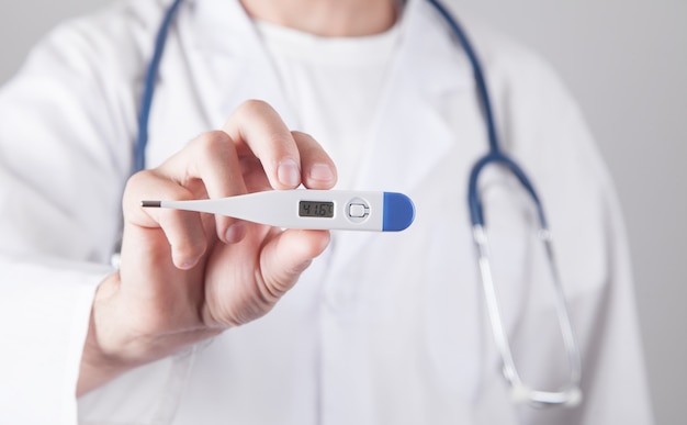 Caucasian doctor holding thermometer. Temperature