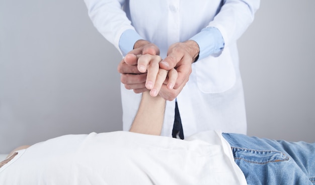 Caucasian doctor massaging patient hand.