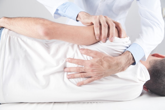 Photo caucasian doctor massaging patient shoulder.