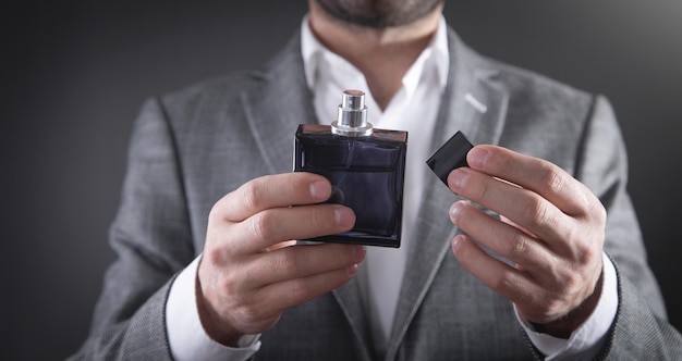 Caucasian elegant man holding perfume