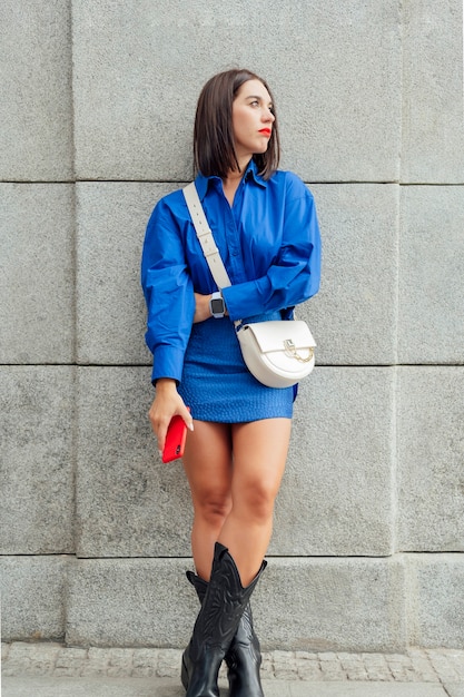 Caucasian European woman leaning on the wall with a mobile phone