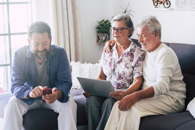 집에 있는 백인 가족은 전화와 노트북 컴퓨터로 현대 기술 장치를 사용하여 즐겁게 시간을 보내고 있습니다.