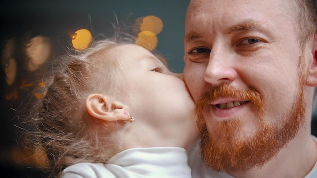 Caucasian family a dad and daughter a girl kissing her father in the cheek