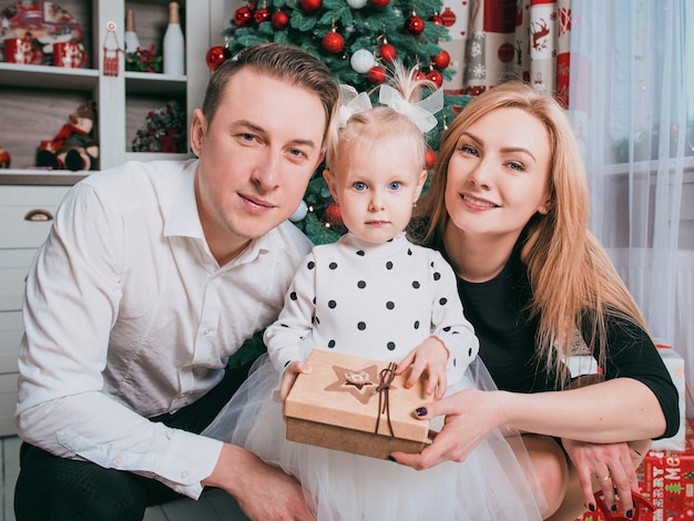 백인 가족 아버지 어머니와 크리스마스 트리 옆에 크리스마스 스웨터를 입은 어린 딸