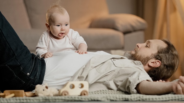 Caucasian family father with little daughter son lie on floor at home Baby girl newborn crawling