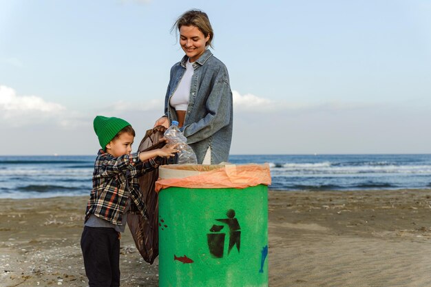 Una famiglia caucasica raccoglie rifiuti di plastica sulla spiaggia la madre insegna a suo figlio a mantenere la natura pulita