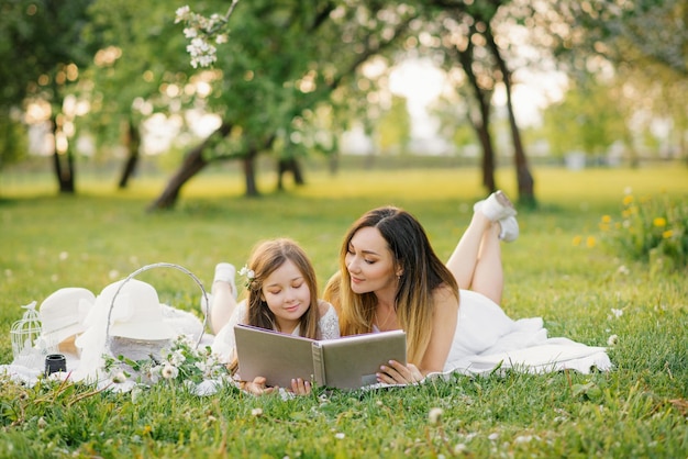 Caucasian family mother and daughter together watching a family photo album in spring at a picnic in the garden the concept of family values generations and memories