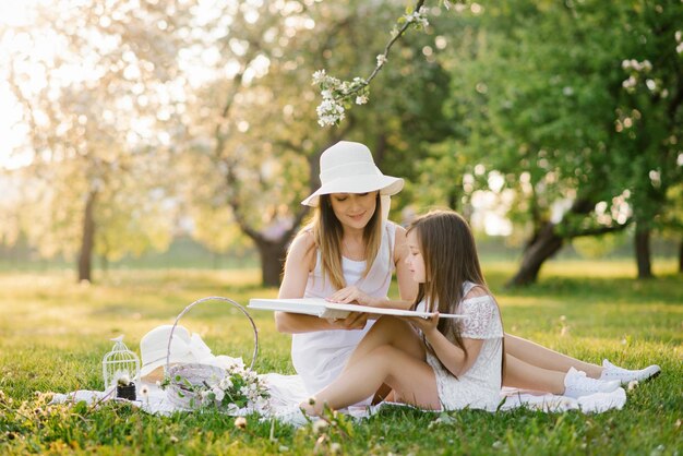 Caucasian family mother and daughter together watching a family photo album in spring at a picnic in the garden the concept of family values generations and memories