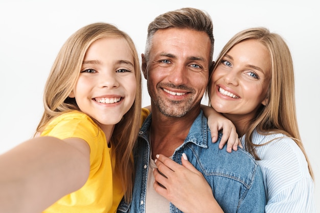 caucasian family woman and man with little girl smiling and taking selfie photo together isolated on white