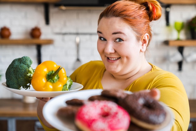 Caucasian fat chubby plus size plump woman choosing between\
helathy and junk food