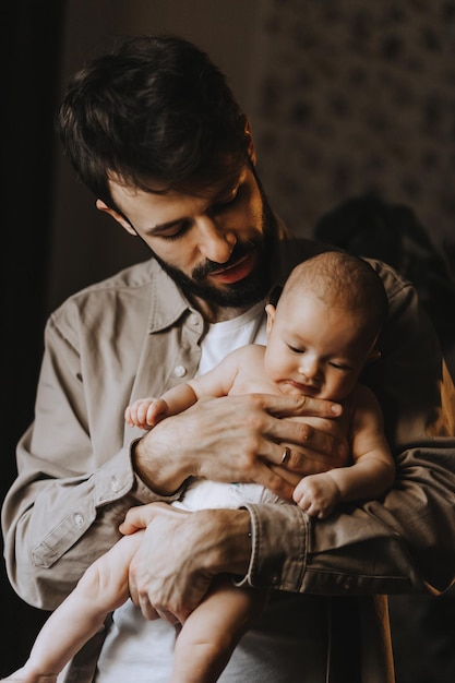 Caucasian father kissing newborn baby Parent holding rocking child daughter son in hands Authentic lifestyle parenting fatherhood moment Single dad family home life Toned